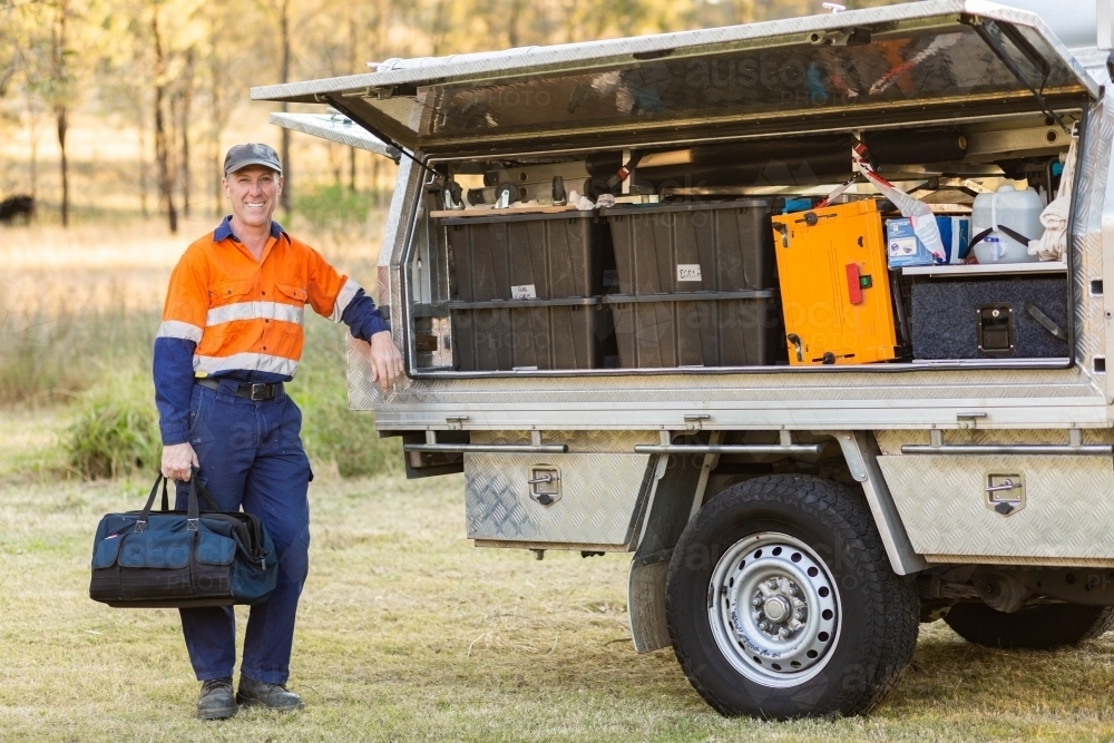 Happy tradie leaning on back of his work ute - Australian Stock Image