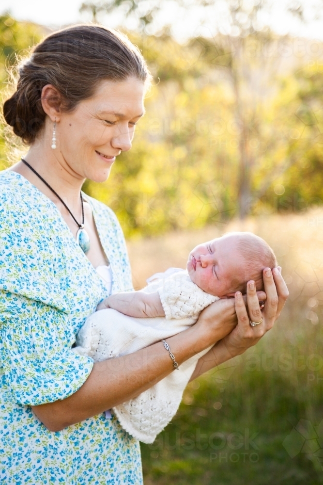 Happy woman holding her newborn daughter outside - Australian Stock Image