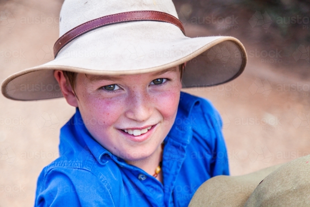 Happy young boy with freckles and hat smiling at camera - Australian Stock Image