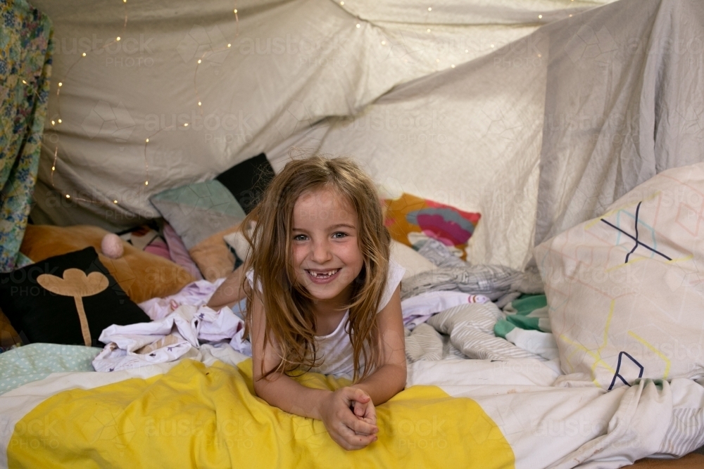 Happy young girl smiling in cubby house tent - Australian Stock Image