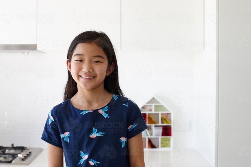 Happy young Japanese girl in kitchen - Australian Stock Image