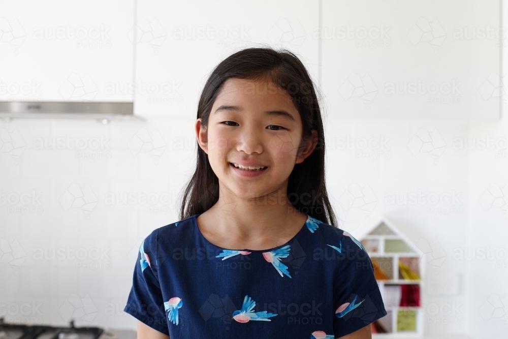 Happy young Japanese girl in kitchen - Australian Stock Image