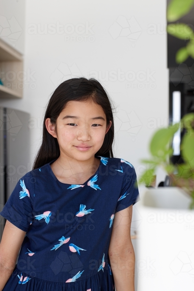 Happy young Japanese girl in kitchen - Australian Stock Image