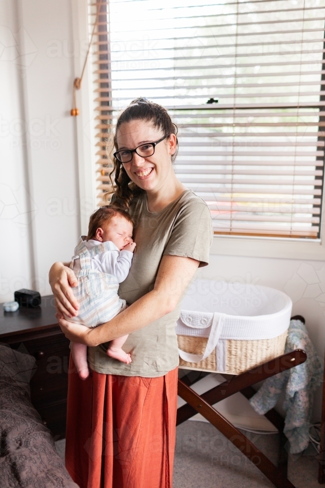 Happy young mum in her twenties holding her new-born - Australian Stock Image