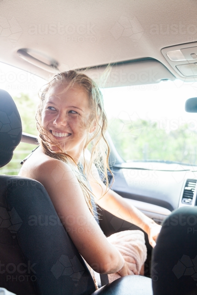 Happy young woman in passenger seat of car coming home from a beach day with friends - Australian Stock Image