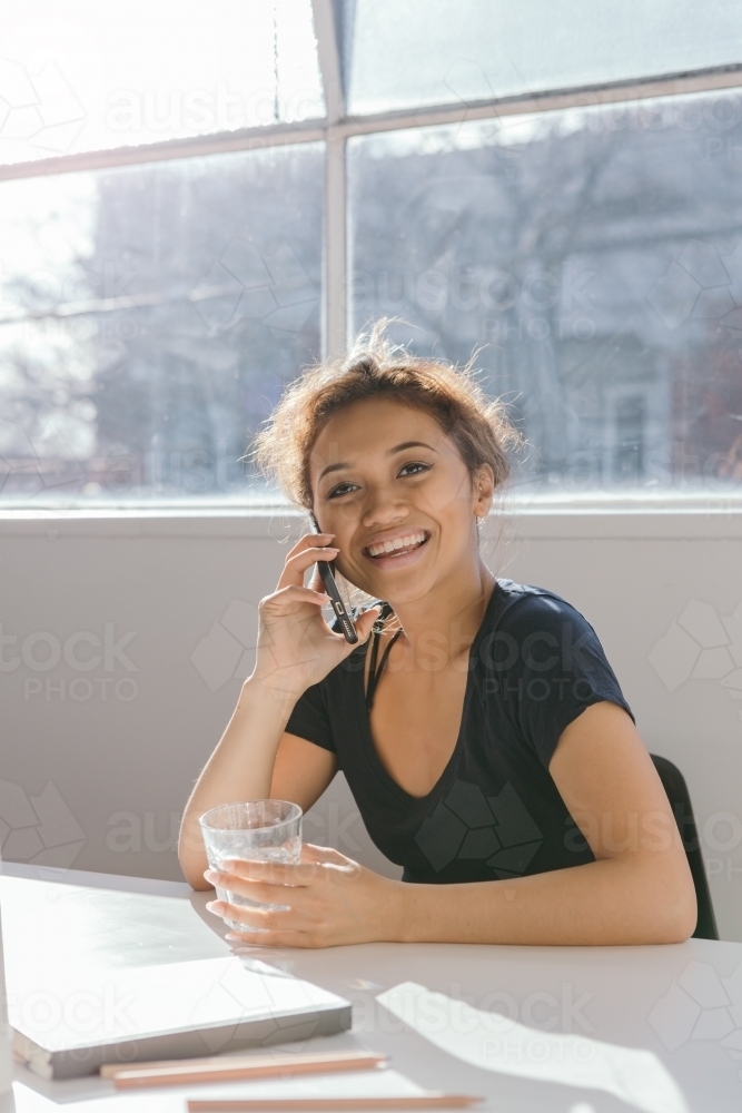 Happy young woman on the phone looking at camera - Australian Stock Image