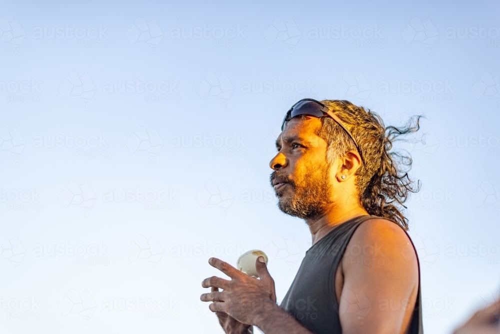 head and shoulders of aboriginal man in profile against blue sky - Australian Stock Image