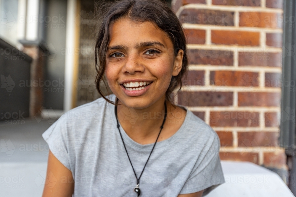 head and shoulders of happy girl with a wide smile sitting outside home - Australian Stock Image