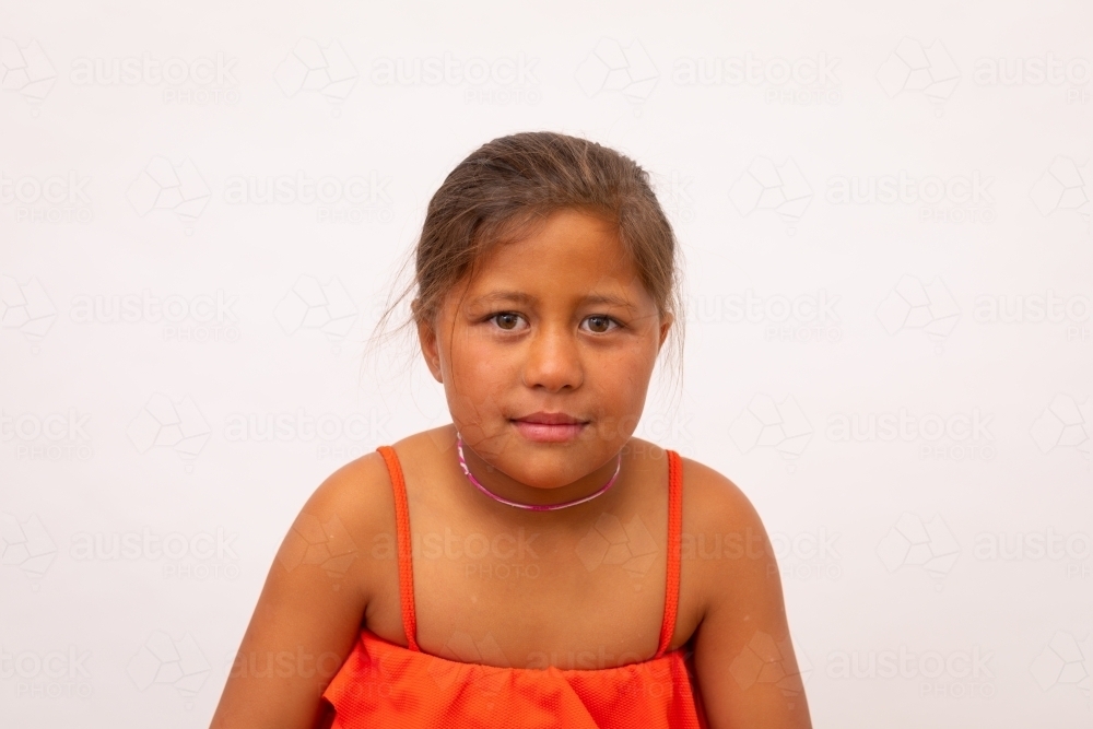 Head and shoulders of Maori child on plain background looking at camera - Australian Stock Image