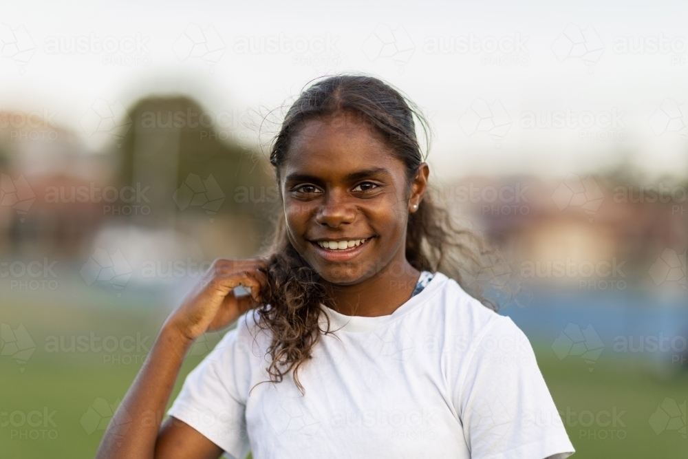 head and shoulders of one aboriginal girl smiling and looking at camera - Australian Stock Image