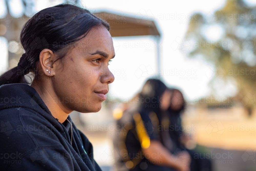 head and shoulders of one girl with more girls blurred in background - Australian Stock Image