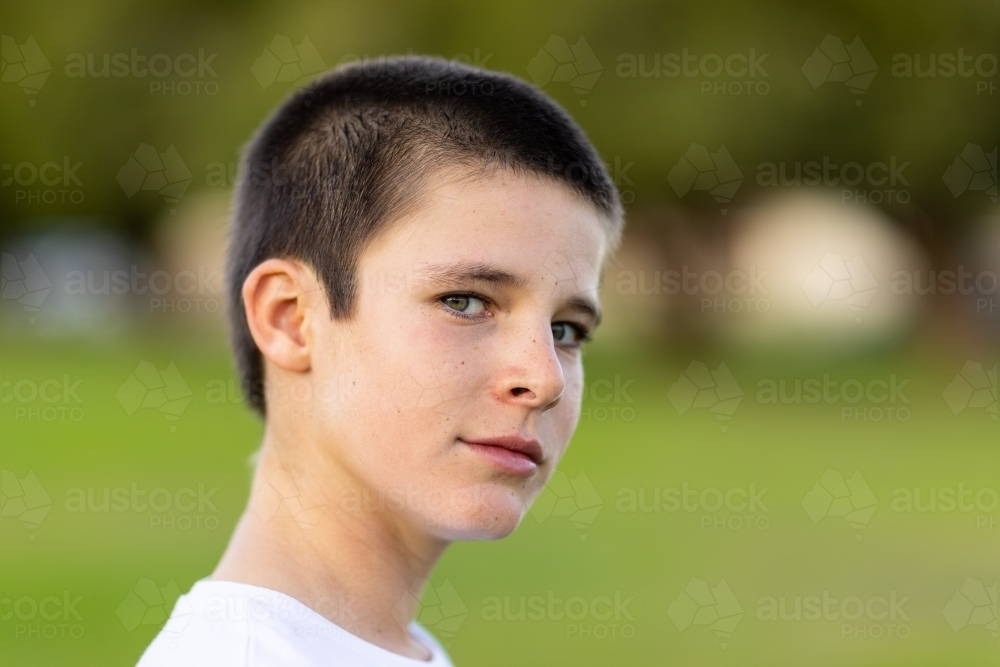 head and shoulders of tween child looking out corner of his eye with blurry background - Australian Stock Image