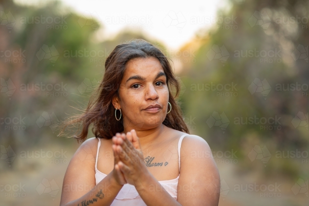 head and shoulders of young lady with hands together outdoors - Australian Stock Image