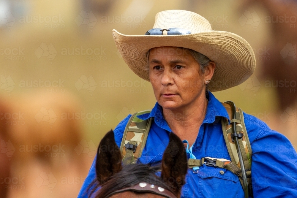 Head shot of an indigenous woman riding a horse. - Australian Stock Image