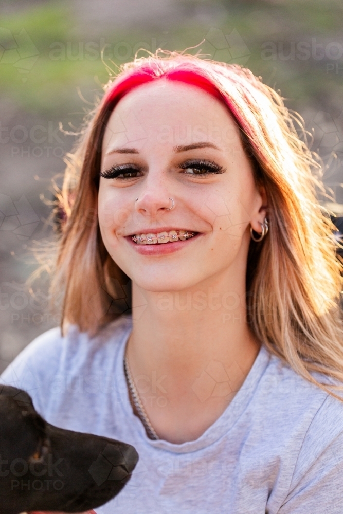 Headshot portrait of happy teenage girl with pink hair outside - Australian Stock Image