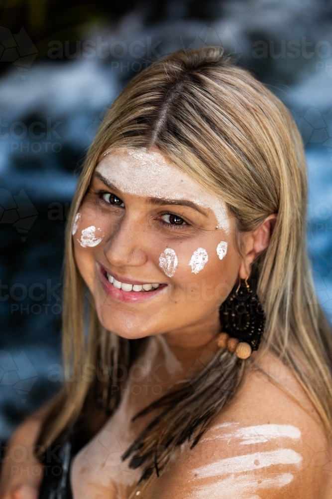 Headshot portrait of smiling First Nations Australian woman with flowing water backdrop - Australian Stock Image