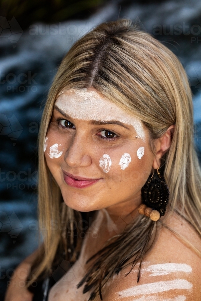 Headshot portrait of smiling First Nations Australian woman with flowing water backdrop - Australian Stock Image