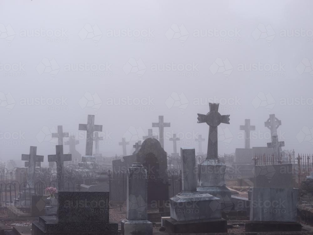 Headstones in a cemetery shrouded in mist - Australian Stock Image