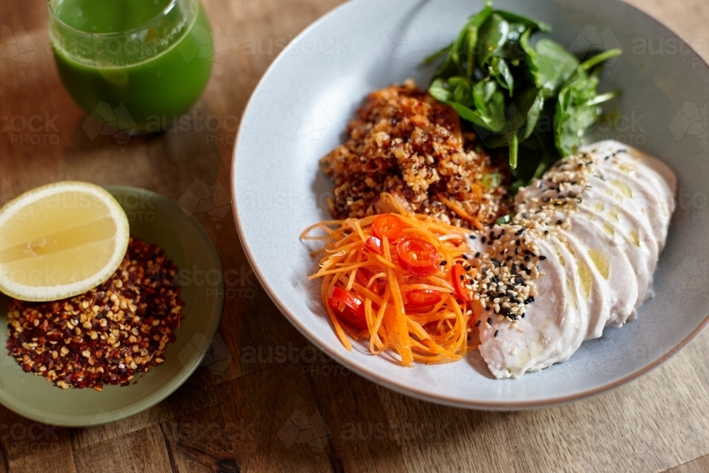 Healthy chicken and salad dish on wooden table in cafe - Australian Stock Image