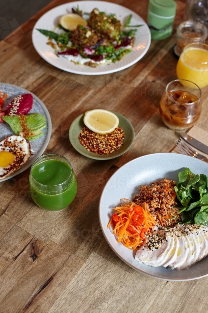 Healthy chicken and salad dish on wooden table in cafe - Australian Stock Image