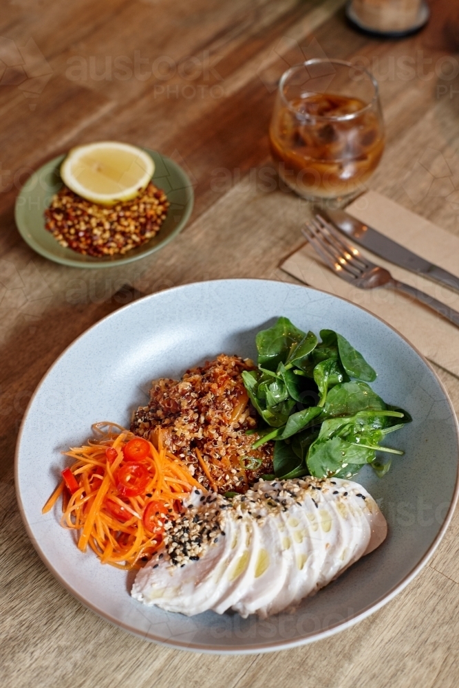 Healthy chicken and salad dish on wooden table in cafe - Australian Stock Image