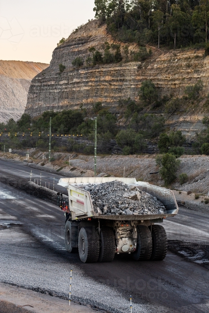 Heavy mine machinery driving away in open cut coal mine moving rocks and earth - Australian Stock Image