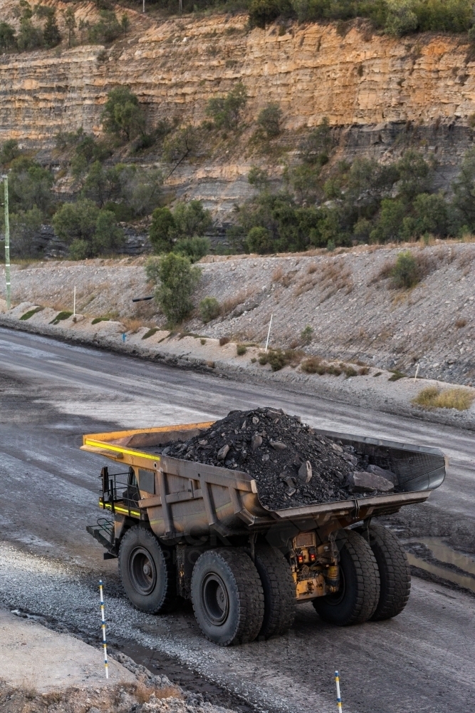 Heavy mine machinery driving away in open cut coal mine moving rocks and earth - Australian Stock Image