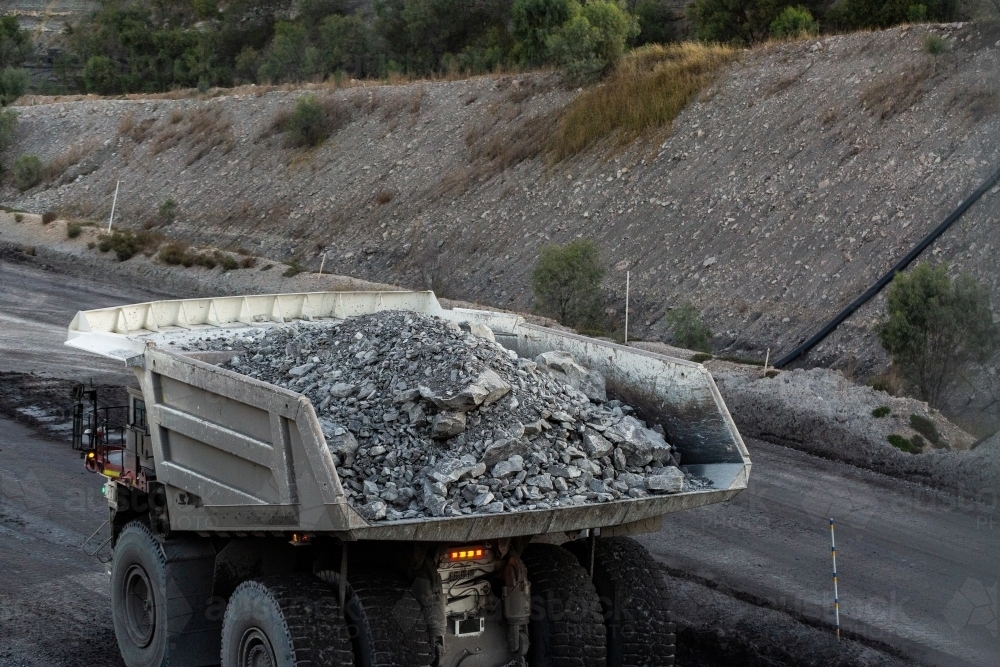 Heavy mine machinery driving away in open cut coal mine moving rocks and earth - Australian Stock Image