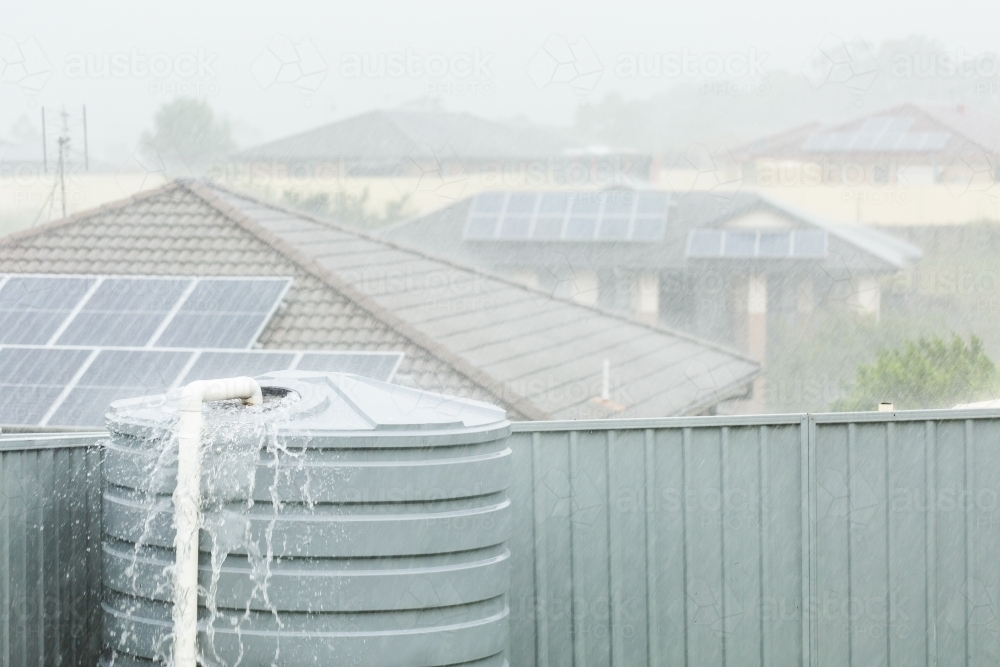 Heavy rainfall in backyard with water overflowing from tank - Australian Stock Image