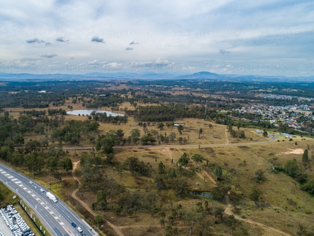 highway with paddock between edge of town as sound buffer - Australian Stock Image