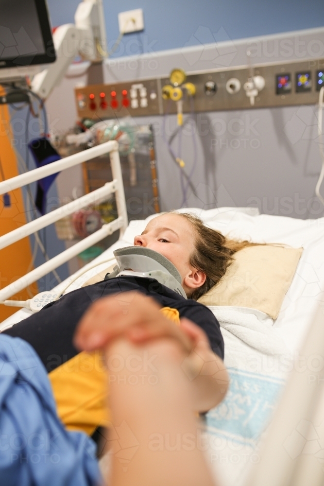 Holding hand of a young girl in hospital wearing a neck brace - Australian Stock Image