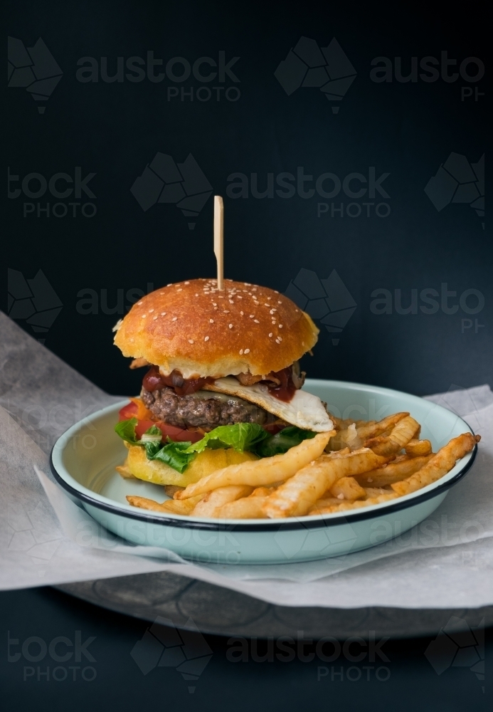 Home made beef burger and oven chips on a plate - Australian Stock Image