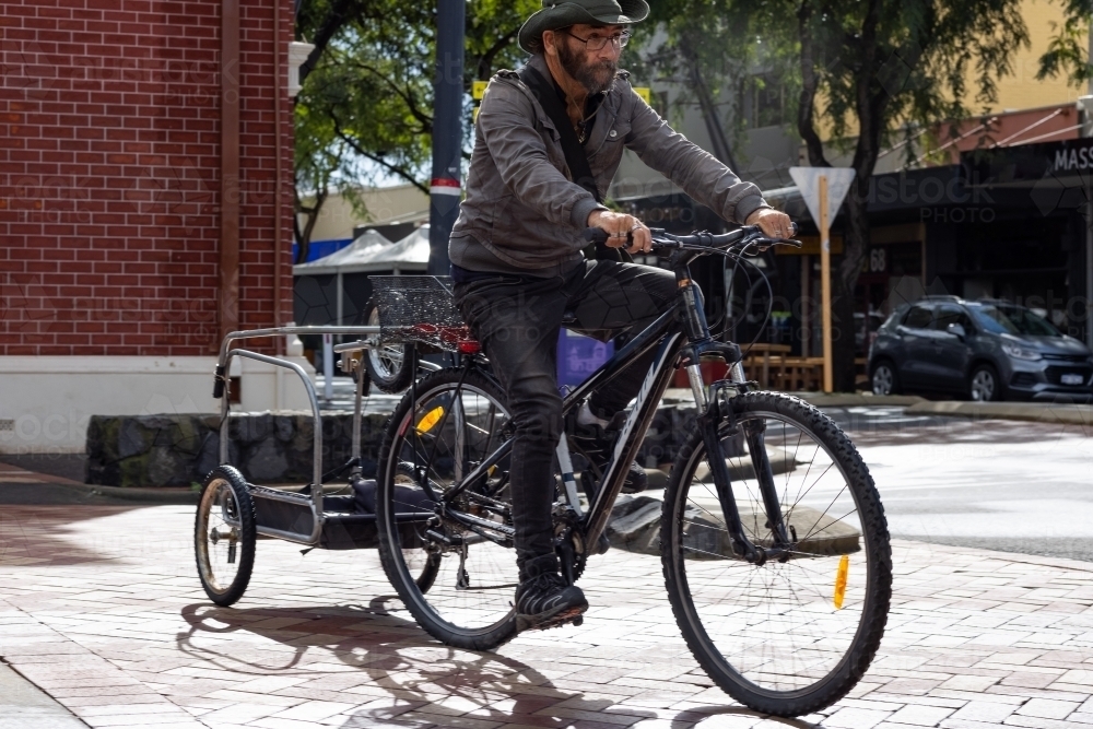 Homeless man on bicycle with jerry-rigged trailer in town - Australian Stock Image