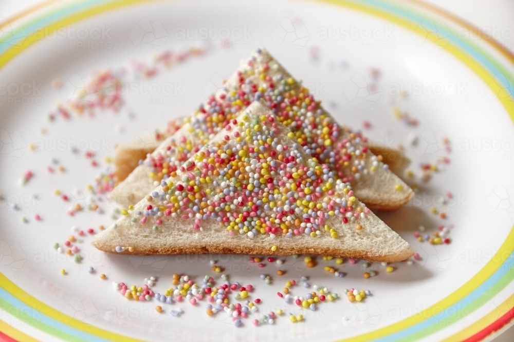 horizontal close up shot of a pair of fairy bread on a white plate with colorful border design - Australian Stock Image