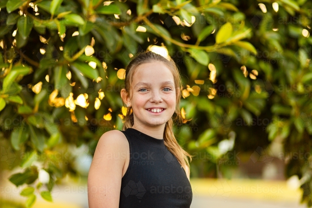 Horizontal portrait of happy tween girl smiling in afternoon - Australian Stock Image