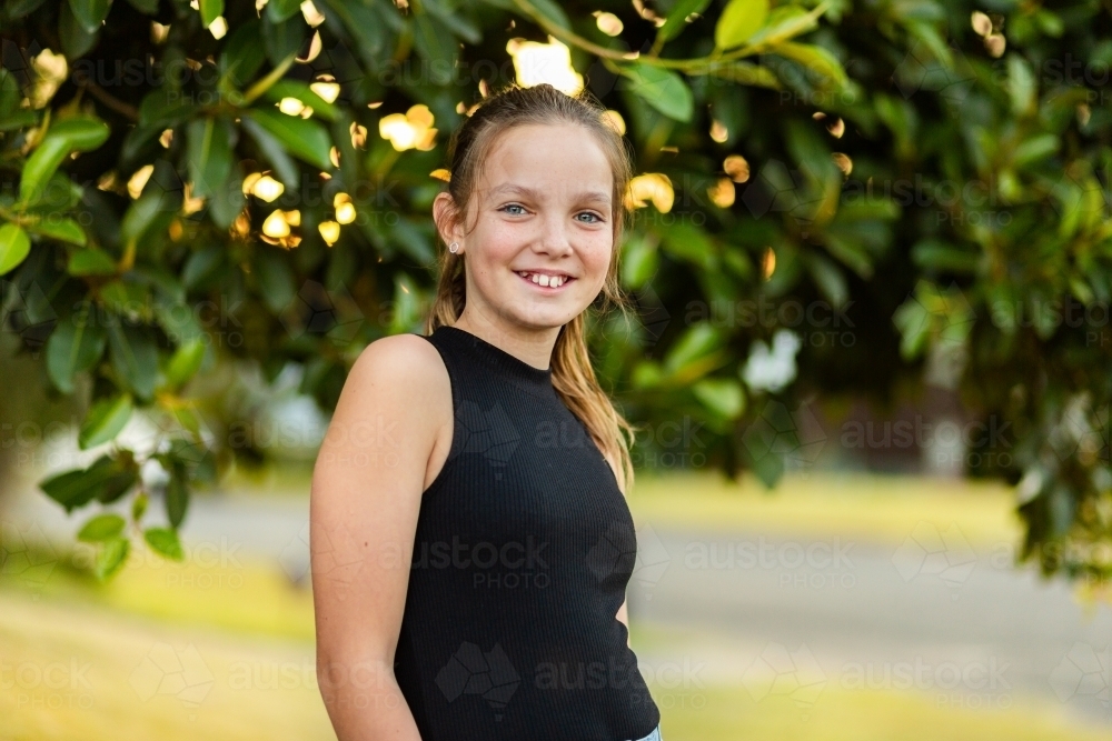 Horizontal portrait of happy tween girl smiling in afternoon - Australian Stock Image