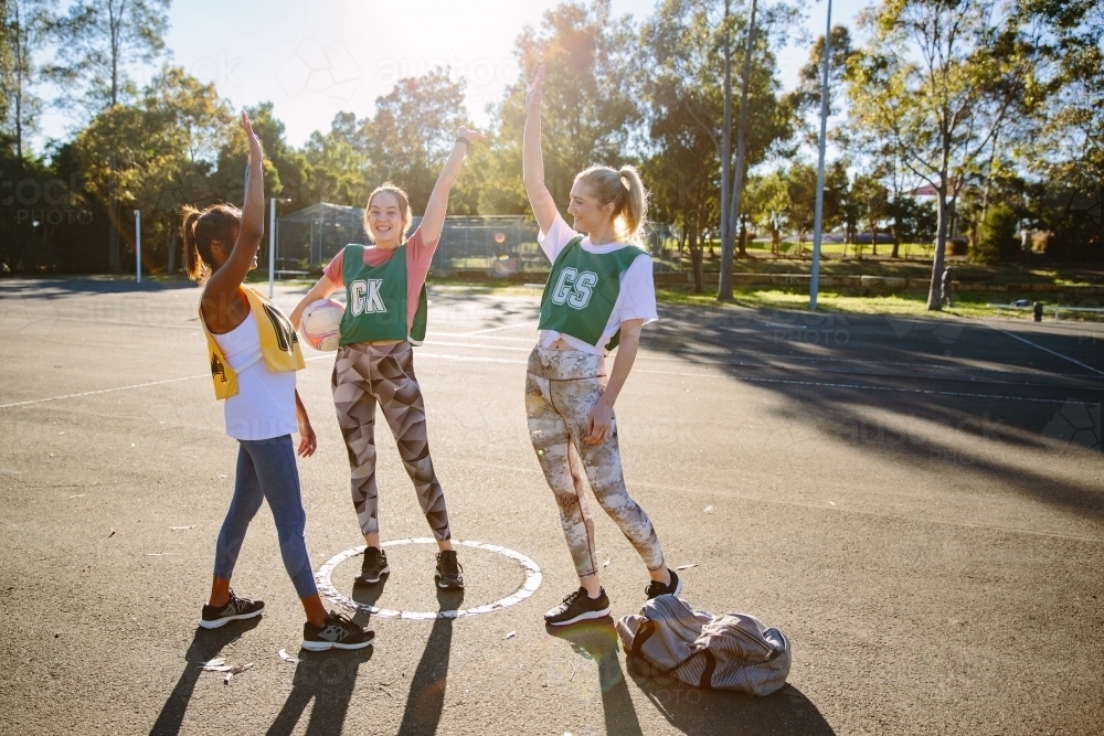 Horizontal shot of 3 women with their arms up on the air while wearing their sportswear - Australian Stock Image