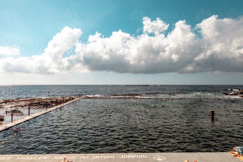 horizontal shot of a beach pool with people swimming on a sunny day - Australian Stock Image