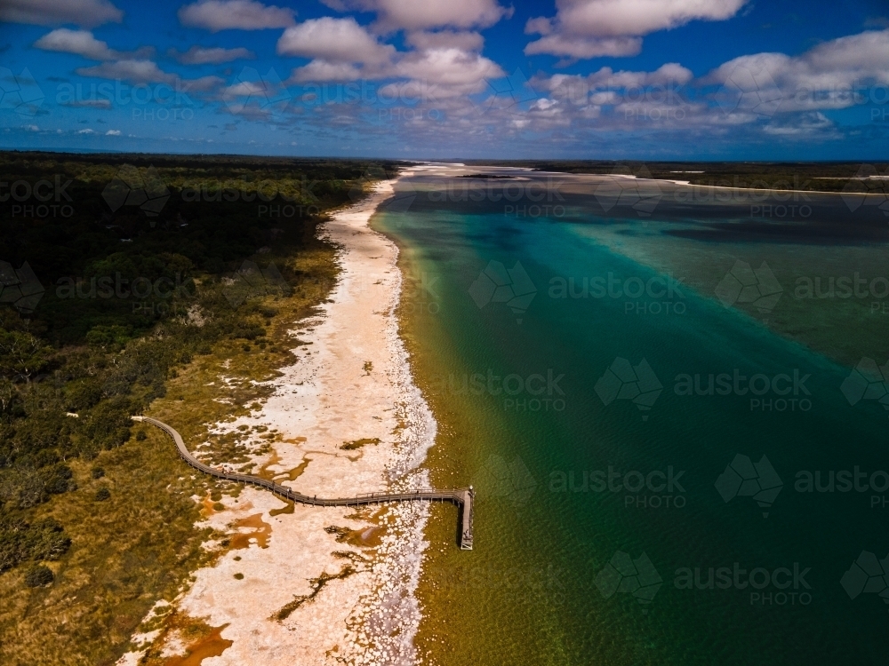 horizontal shot of a beach walkway with bushes, trees and waves on a sunny day - Australian Stock Image