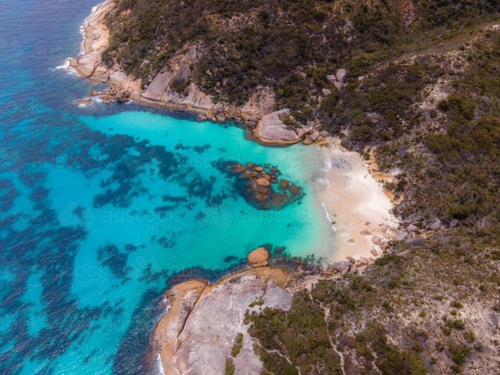 horizontal shot of a beach with bush hills, rocks, trees and white sand - Australian Stock Image