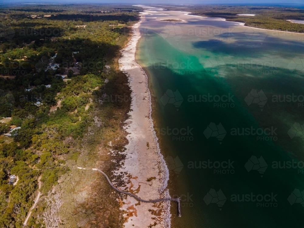horizontal shot of a beach with long shoreline with bushes and trees - Australian Stock Image