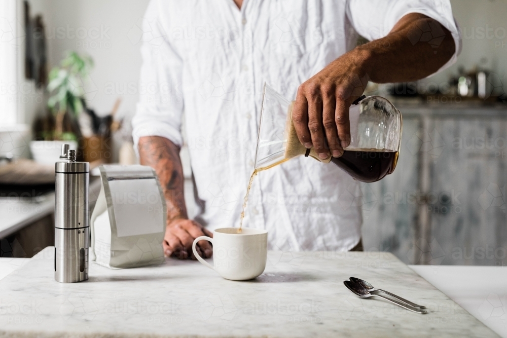 Horizontal shot of a man pouring coffee into  a cup - Australian Stock Image