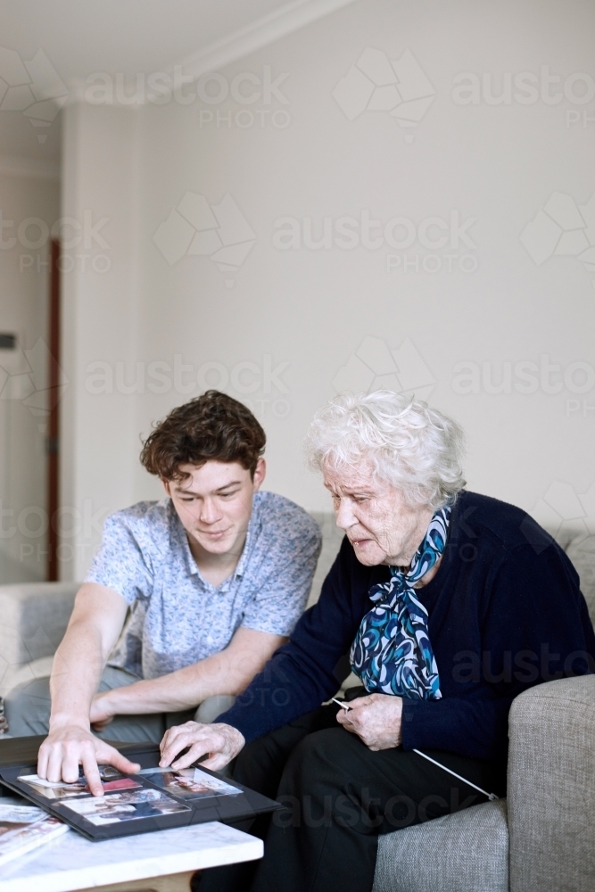 Horizontal shot of a teenage boy and and old woman looking at pictures - Australian Stock Image