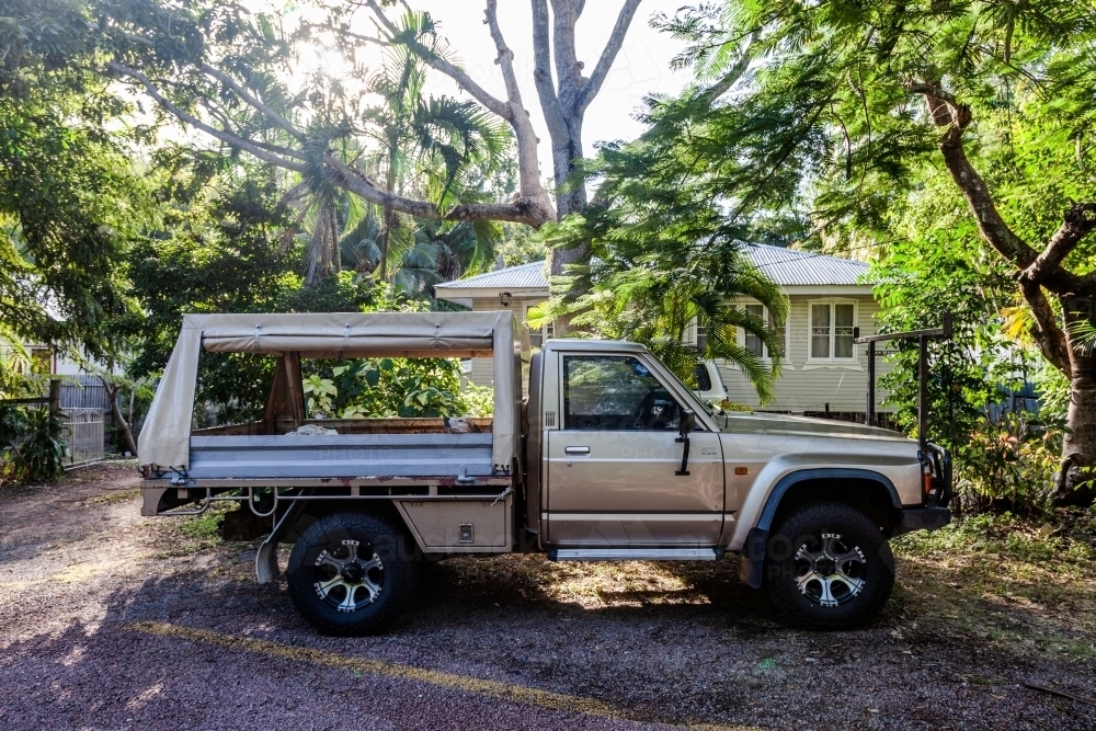 horizontal shot of a ute parked in front of house and trees in the background on a sunny day - Australian Stock Image