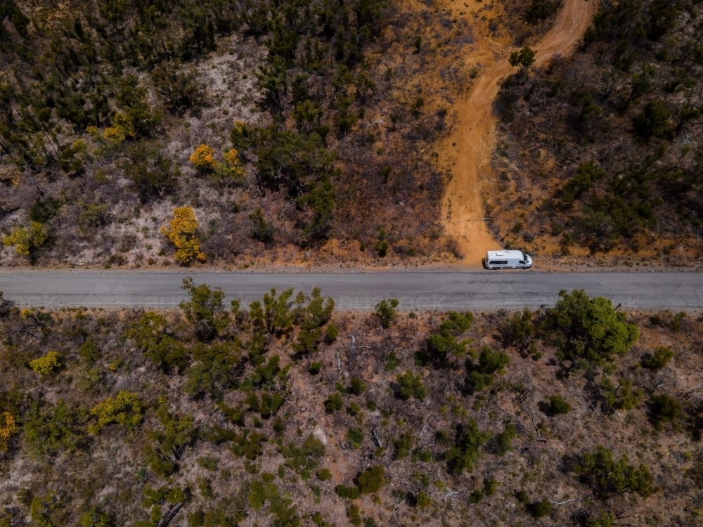 horizontal shot of a white truck parked beside a road with bushes, trees, grass, and dirt road - Australian Stock Image