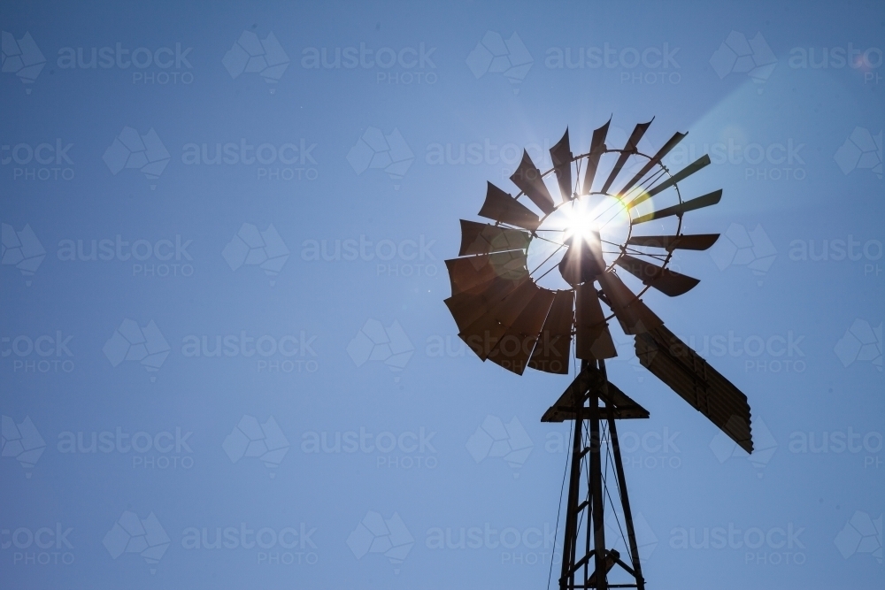 horizontal shot of a windmill silhouette on a sunny day with clear skies - Australian Stock Image