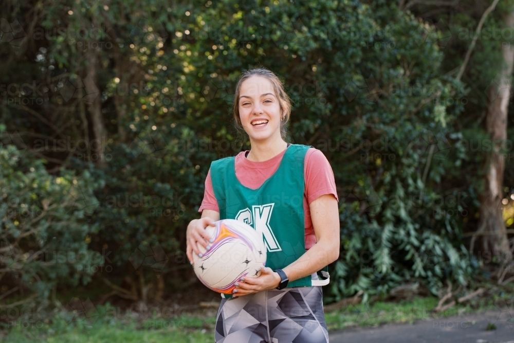 Horizontal shot of a woman holding a ball smiling while looking at the camera - Australian Stock Image