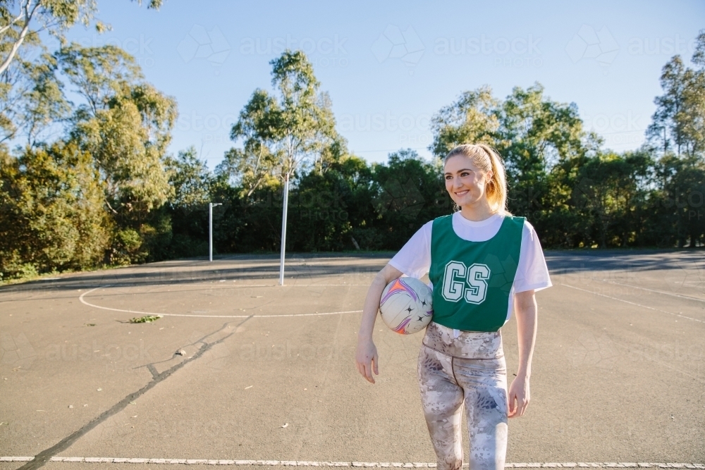 horizontal shot of a young smiling woman holding a net ball in between her hands and her waist - Australian Stock Image