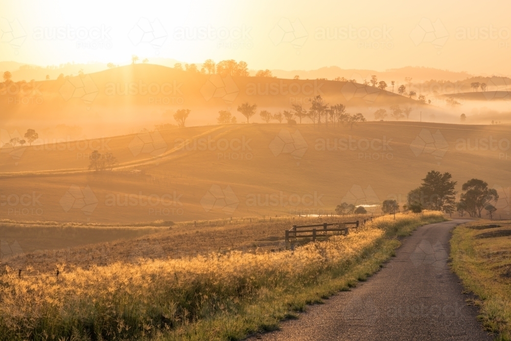 Horizontal shot of an empty road heading toward hills at dawn - Australian Stock Image