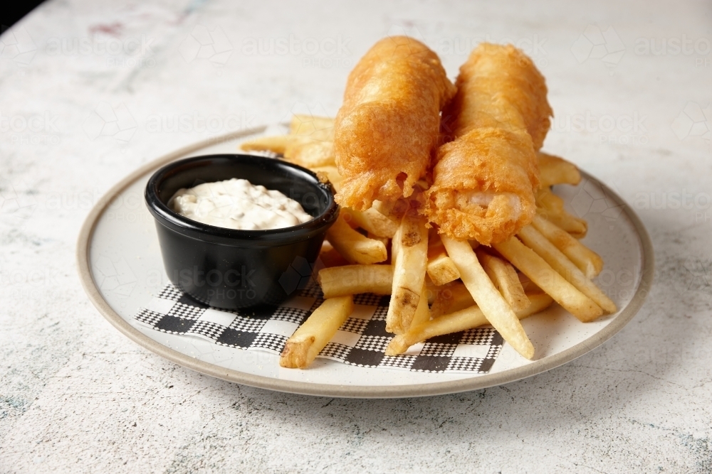 horizontal shot of fish and chips with buttermilk ranch dipping sauce all placed in  a white plate - Australian Stock Image